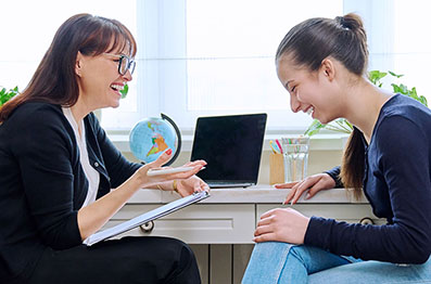 Woman with clipboard sitting across from another woman and both are smiling