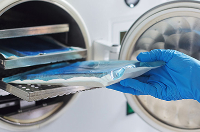 Hand placing zipped packets into sterilization machine
